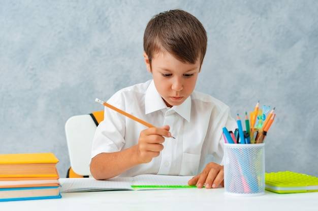 Снова в школу счастливый улыбающийся ученик рисует за партой школьник решает домашнее задание мальчик из эл