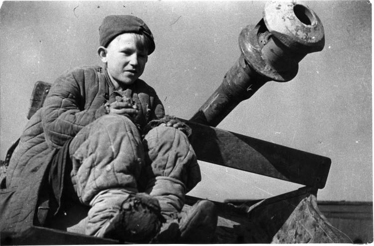 Советский подросток сидит у ствола брошенного при немецком отсуплении артиллерийского орудия